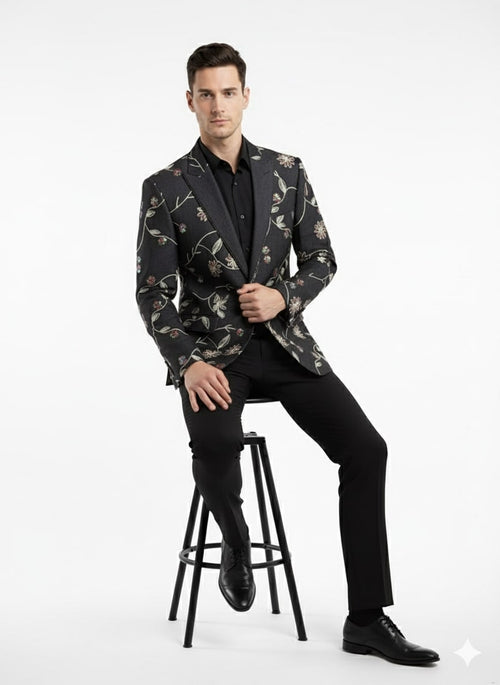 Black floral embroidered men's blazer. Tailored fit, structured silhouette. Black fabric with colorful floral embroidery. Peak lapels, single-button closure. Formal design, ideal for evening events.
