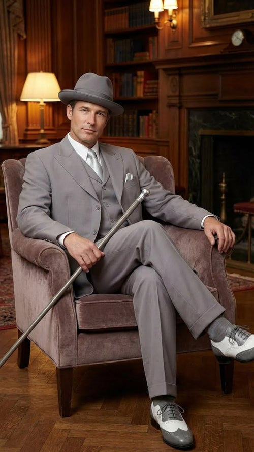 Men's gray zoot suit: tailored fit, wide-leg trousers, matching hat, vest, smooth material. Includes two-tone 1920s-style shoes (gray/white).