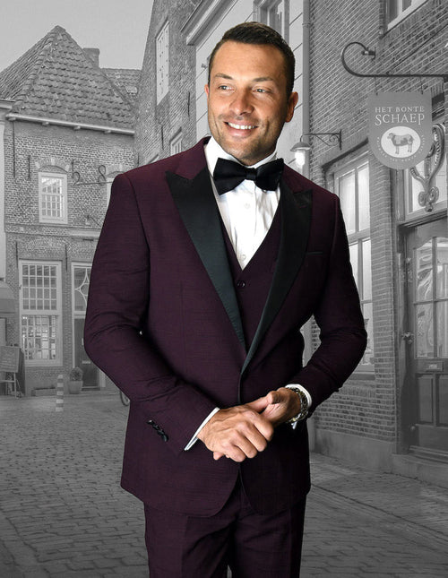 Burgundy men's tuxedo with wide peak lapel and buttoned vest. Tailored fit, textured fabric, ideal for prom or formal events. Stylish and structured.
