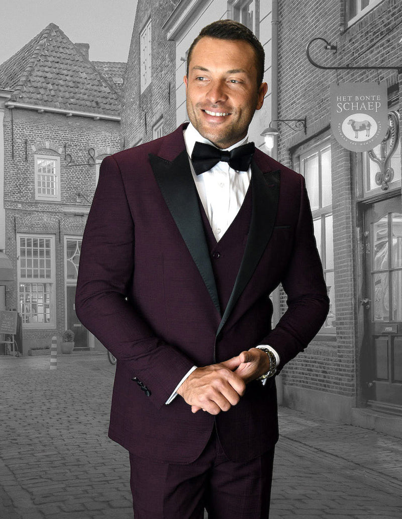 Burgundy men's tuxedo with wide peak lapel and buttoned vest. Tailored fit, textured fabric, ideal for prom or formal events. Stylish and structured.
