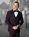 Burgundy men's tuxedo with wide peak lapel and buttoned vest. Tailored fit, textured fabric, ideal for prom or formal events. Stylish and structured.
