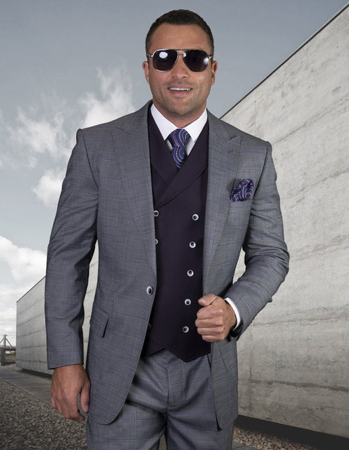 Men's blue suit with a subtle check, peak lapels, and a single-button closure. Features pleated pants and a dark waistcoat for a formal, tailored look.
