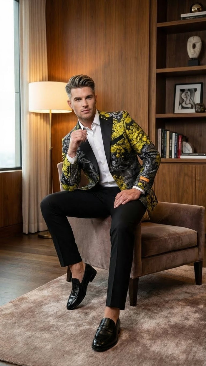 Men's yellow tuxedo with black & gold floral blazer. Structured shape, peak lapels, long sleeves. Intricate floral design. Slim fit, paired with black trousers & loafers.
