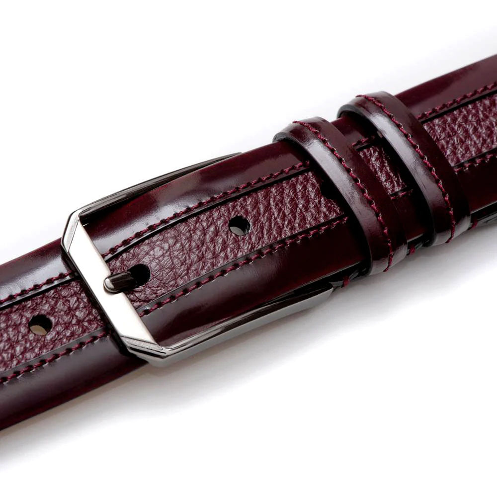 Burgundy Mezlan deerskin belt. Smooth, glossy leather with textured detail and contrasting stitching. Adjustable with a geometric metal buckle.
