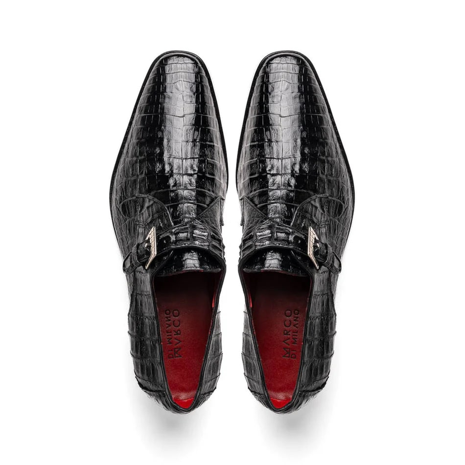Black caiman crocodile leather dress loafers with single monk strap. Pointed toe, textured scale pattern, adjustable metal buckle. Red interior lining.

