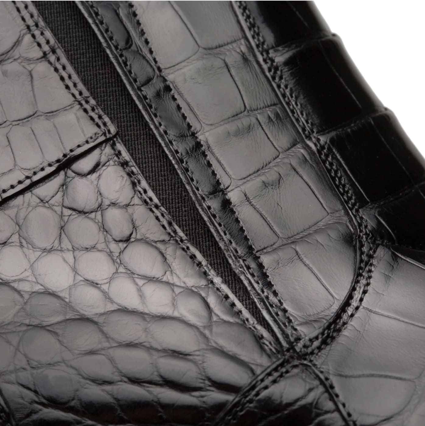 Black Belucci alligator zipper boot: sleek pointed-toe, ankle-height silhouette. Shiny black alligator leather upper with visible scales and glossy finish. Elastic side panels for comfort. Inner zipper for easy wear.
