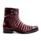 Burgundy Belvedere Libero boot with quilted shaft & cap toe. Tapered shape, metal buckle accent. Low stacked heel, smooth sole, caiman leather. Structured design.
