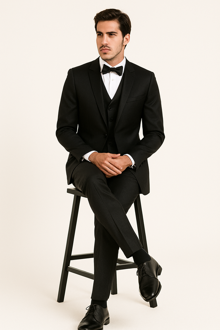 Alberto Nardoni's "Black Majesty" tuxedo: black jacket with notched lapel, single-button closure; white shirt; black bow tie; straight-leg black trousers. Smooth, solid black fabric.
