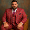 Men's red plaid three-piece suit. Bold checkered pattern with deep red, white, and black accents. Includes vest and matching pants. Smooth, tailored fabric with a structured fit.
