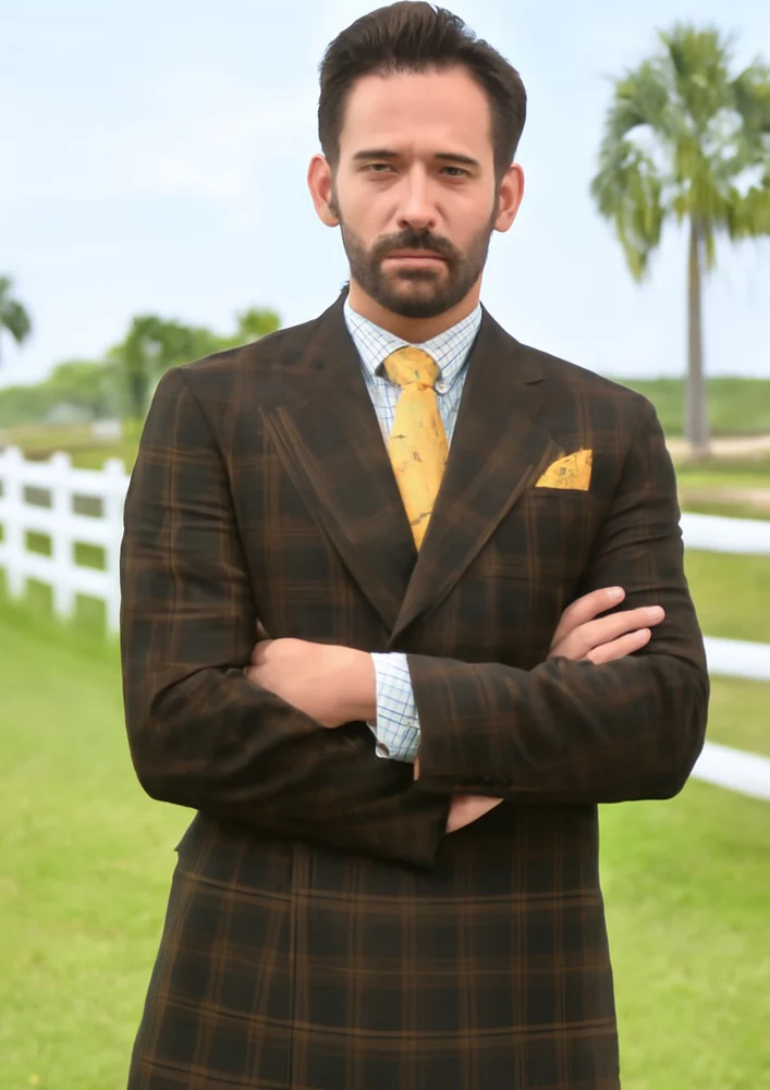 Men's wool double-breasted suit. Brown plaid pattern, peak lapels, fitted tailoring. Classic checked design in dark and light brown. Includes two front pockets.
