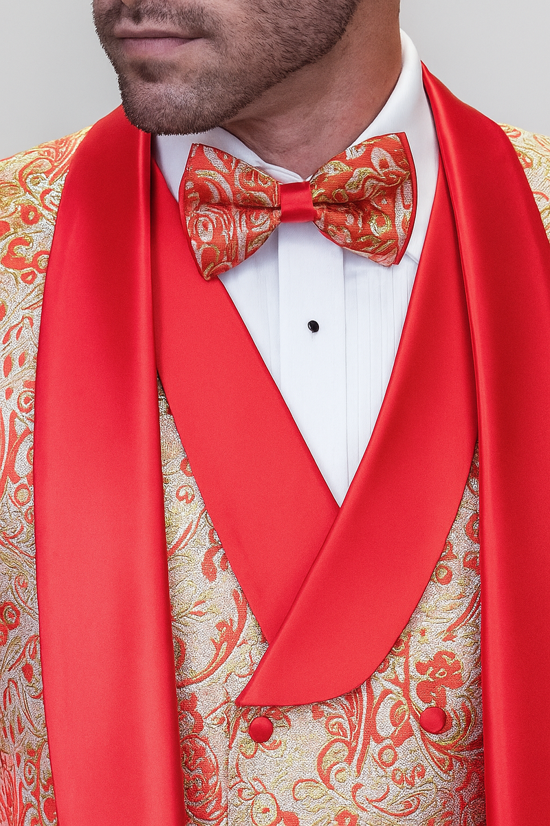 Coral orange men's shiny paisley wedding tuxedo. Patterned jacket with gold/orange paisley, red satin shawl collar, matching bow tie. White dress shirt. Shiny materials, structured form.
