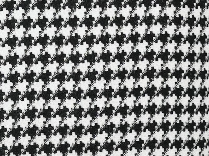 Black houndstooth hybrid double-breasted jacket. Structured, tailored fit with repeating black and white pattern. Textured fabric, potentially outerwear material. Formal style, double-breasted buttons.

