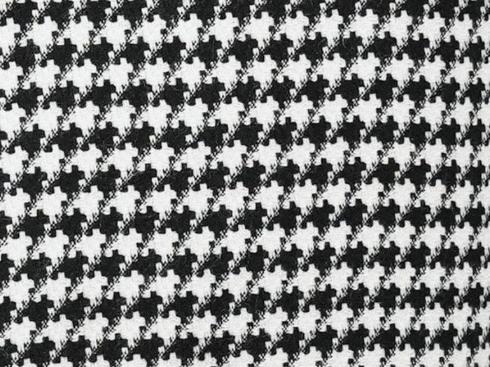Black houndstooth hybrid double-breasted jacket. Structured, tailored fit with repeating black and white pattern. Textured fabric, potentially outerwear material. Formal style, double-breasted buttons.
