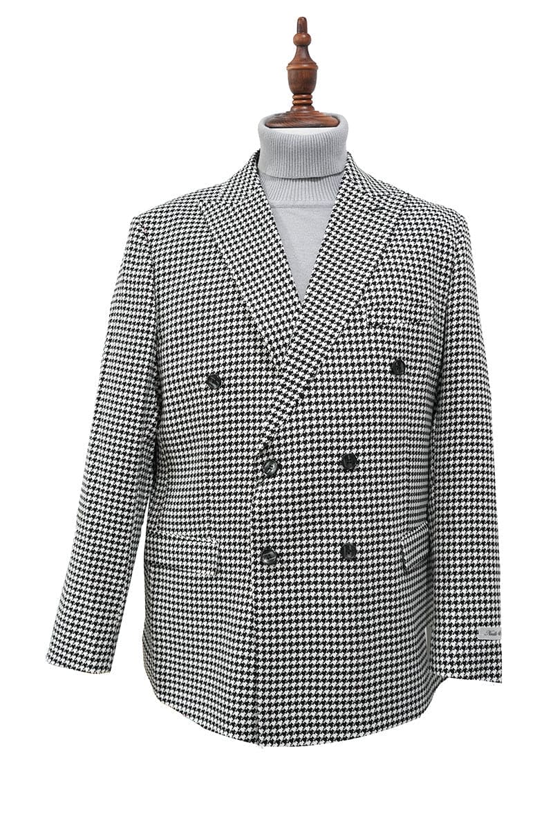 Black houndstooth double-breasted jacket with structured silhouette. Wide lapels, front pockets, and six decorative buttons. Long, slightly tapered sleeves with contrasting cuffs. Fully lined. Bold black and white houndstooth pattern.

