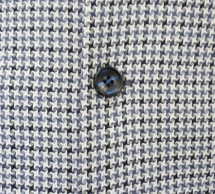 Blue houndstooth double-breasted jacket with a light/dark blue pattern. Features a black, four-hole button detail centered on the fabric.
