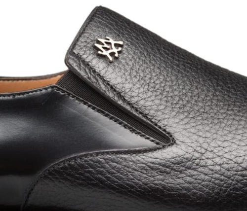 Mezlan black calfskin/deerskin slip-on with sleek silhouette. Textured upper, elastic sides for fit, and a small metallic logo. Low-profile design.
