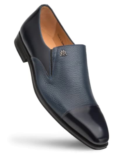 Blue calfskin and deerskin slip-on dress shoe. Rounded, glossy-capped toe, textured body. Flat sole with slight heel. Features an emblem on the upper.
