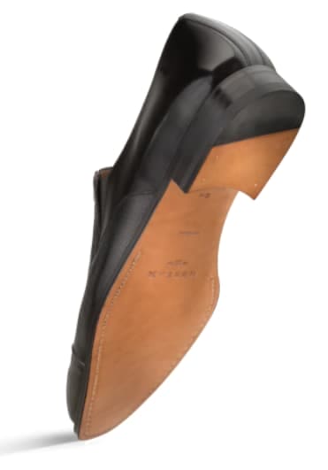Milani black calfskin slip-on with deerskin interior. Sleek, low-profile design, rounded toe. Smooth calfskin upper, light brown leather outsole. Classic, minimalist aesthetic.
