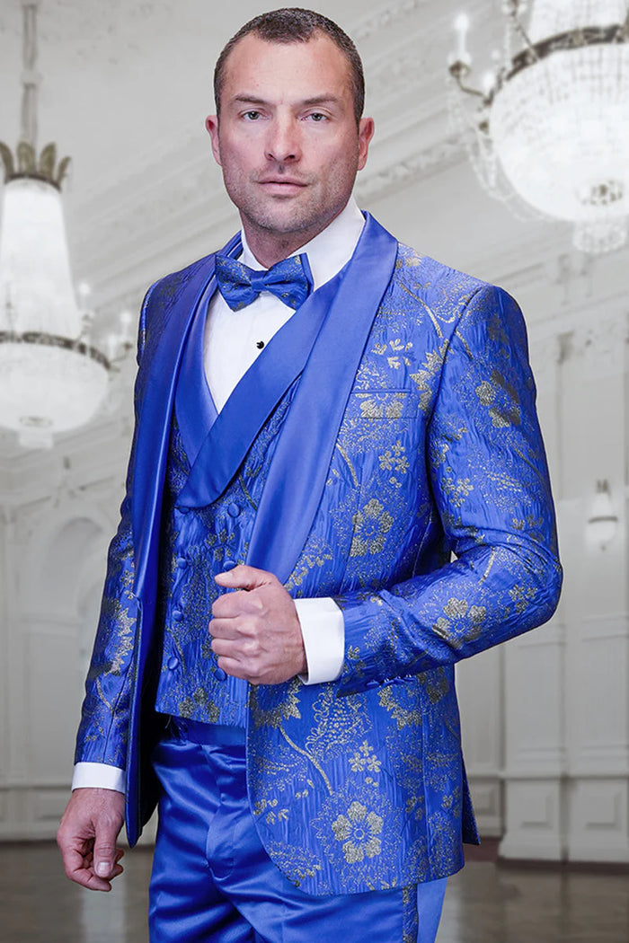 Royal blue tuxedo with paisley lace and gold floral patterns on a satin finish. Double-breasted vest with matching buttons. Peaked lapels. White shirt cuffs. Structured shape for a formal look.

