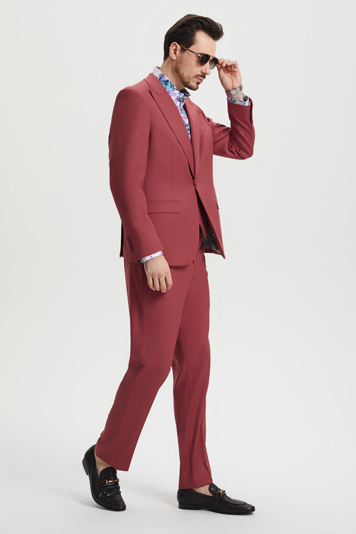 Men's coral blush pink suit. One-button peak lapel jacket with chest pocket. Slim-fit pants. Tailored silhouette, solid, lightweight fabric with subtle sheen.
