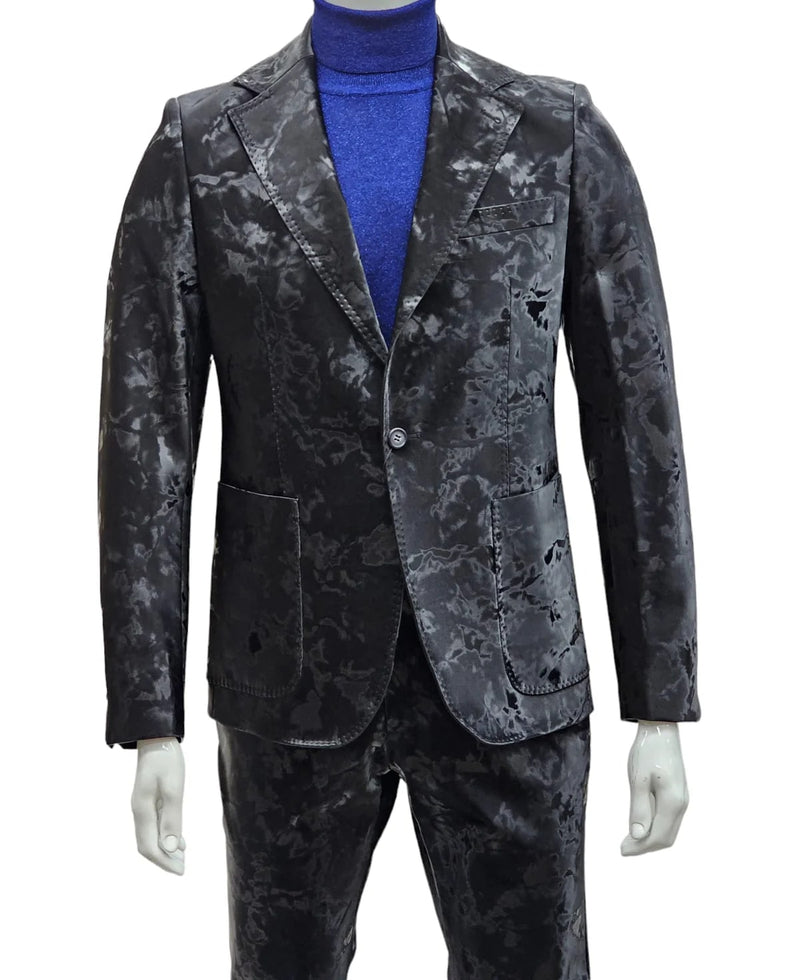 Black camouflage two-piece suit: slim fit, single-button blazer with notched lapel and pockets. Smooth, glossy fabric with textured camo. Matching slim-fit trousers.
