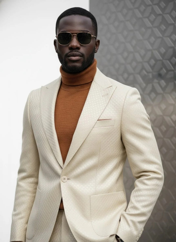 Ivory suit with basket weave, peak lapel, and one-button closure. Slim fit design. Features a single breast pocket and two front pockets.

