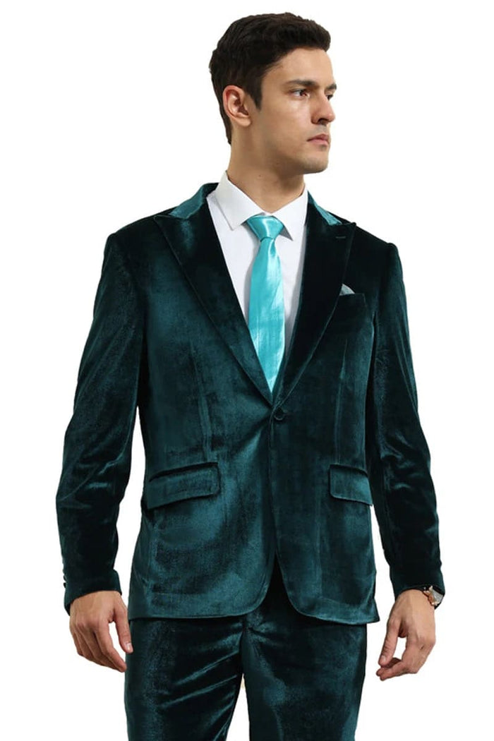 Teal green slim fit velvet men's suit. Single-breasted jacket with peak lapels, two front pockets, and matching trousers. Smooth, luxurious fabric.
