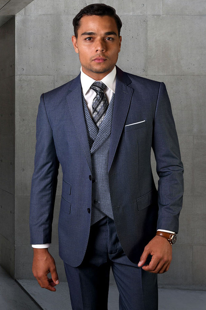 Indigo blue wool suit with a micro plaid vest. Tailored fit, two-button jacket with notched lapel and flap pockets. Consistent color. White shirt and patterned tie complete the look.
