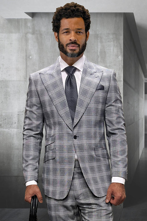 Men's grey windowpane plaid suit. One-button peak lapel, tailored fit. Features two front pockets. Complemented by a white shirt and dark tie. Elegant, designer style.
