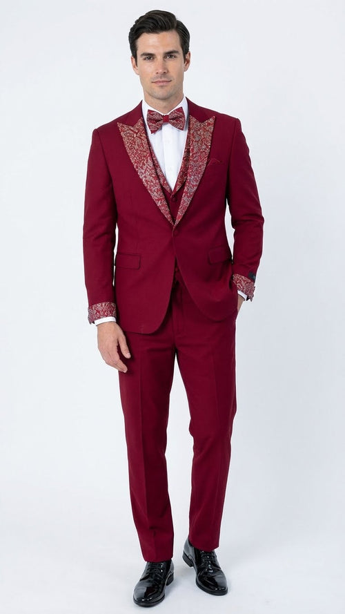 Burgundy tuxedo suit with white embellished shawl lapel & matching trousers. Features decorative cuffs, white shirt, & burgundy bow tie. A sophisticated, fitted look.
