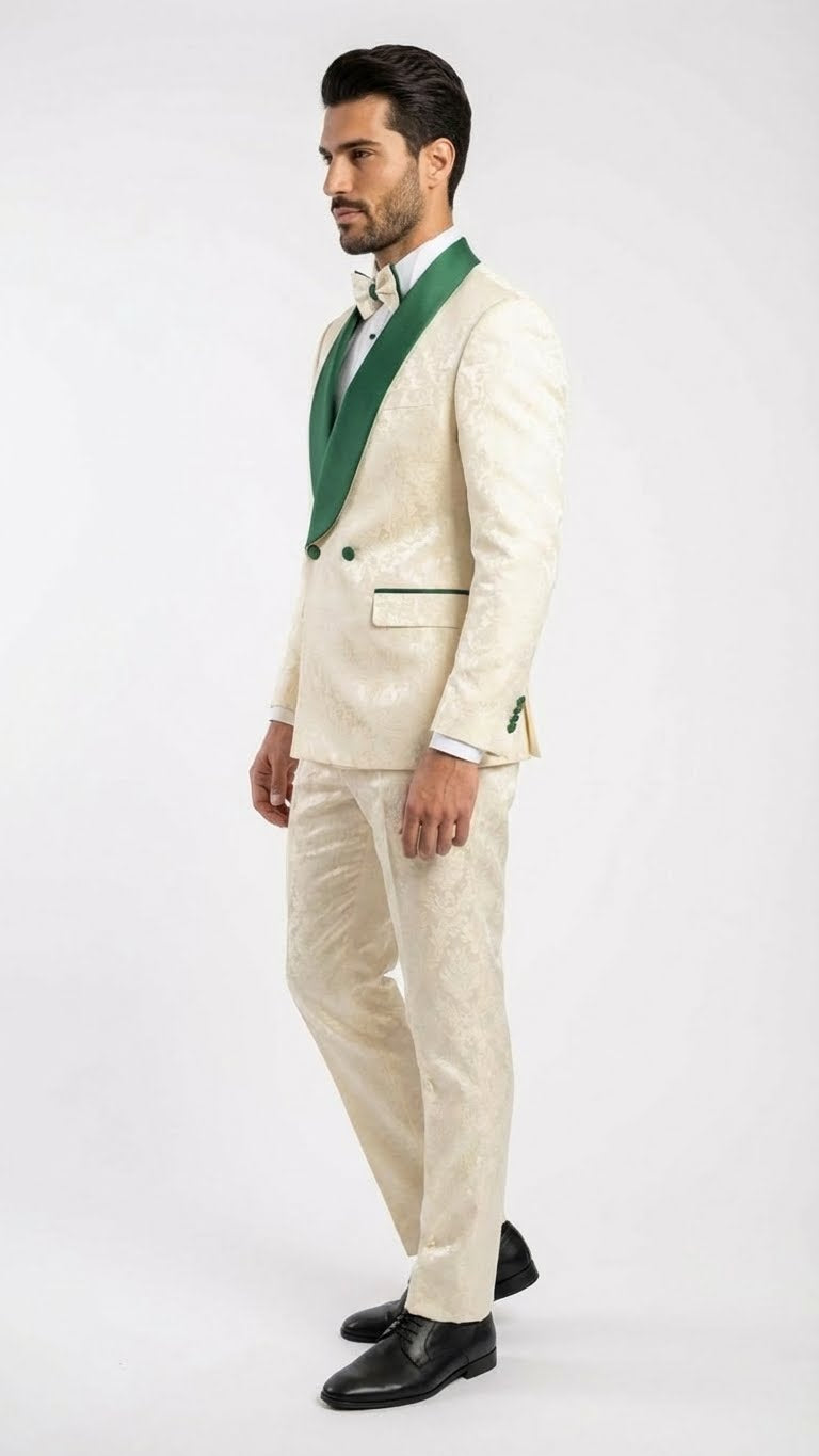 Ivory tuxedo suit with emerald green accents. Jacquard pattern, shawl collar, and two-button closure on jacket. Tailored ivory pants. Green pocket square. Black dress shoes complete the formal look.
