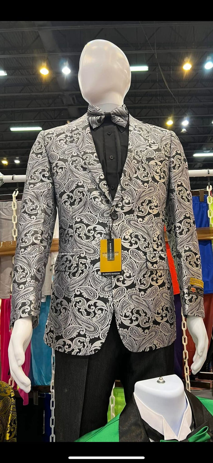 Men's slim fit black & silver paisley tuxedo jacket. Features intricate patterns, smooth fabric, and a matching bow tie. Includes black pants, single-button closure, & notched lapels.
