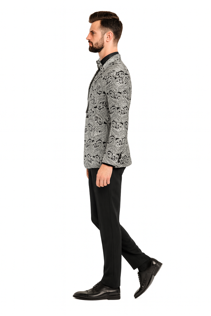 Men's tuxedo jacket: Slim fit, black & silver paisley, structured collar, single-button closure. Paired with black pants & bow tie. Smooth fabric, tailored sleek profile.
