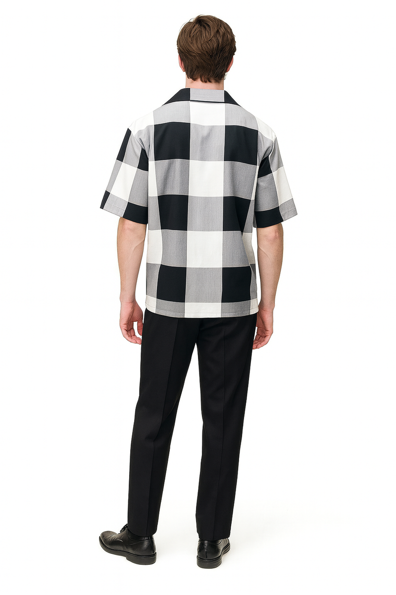Men's short-sleeve shirt with black & white checkered pattern. Relaxed fit, collar, and lightweight material. Part of a two-piece outfit paired with black trousers.
