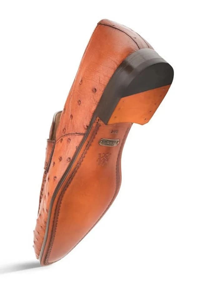 Mezlan Lisbon slip-on loafer in brandy ostrich leather. Streamlined design with pointed toe & raised heel. Features natural texture, stitched trim, metal logo. Slightly thicker heel for structure.
