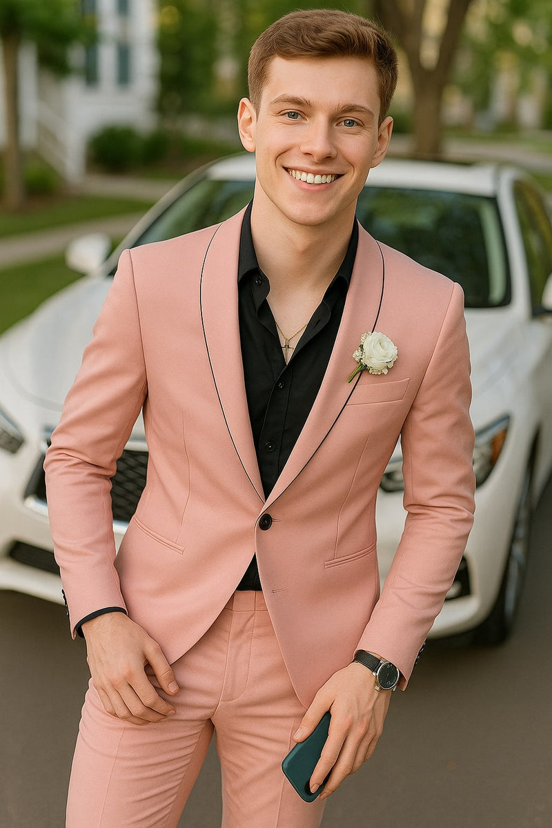 Men's slim fit pink tuxedo. Structured jacket with black trim and a single-button closure. Paired with matching slim-fit trousers. Smooth, light pink material with a subtle sheen.
