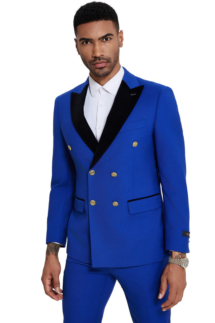 Bright blue double-breasted men's wedding suit. Black velvet peak lapel, gold buttons, side pockets. Tailored, fitted silhouette with sharp lines.
