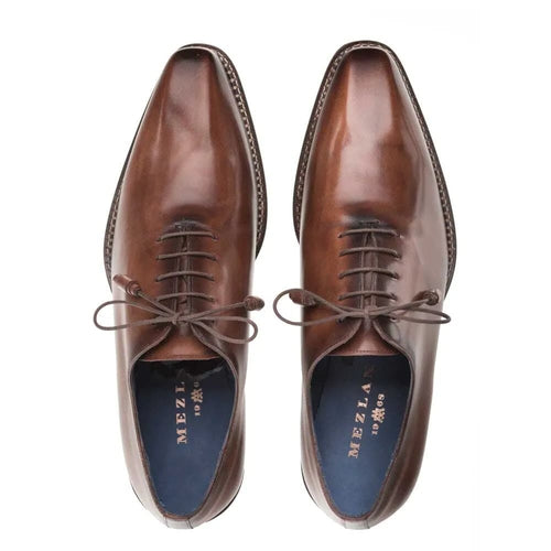 Mezlan men's plain toe shoe in brown calfskin. Smooth leather upper with rounded toe and decorative stitching. Lace-up closure, thin sole, and contrasting blue lining.
