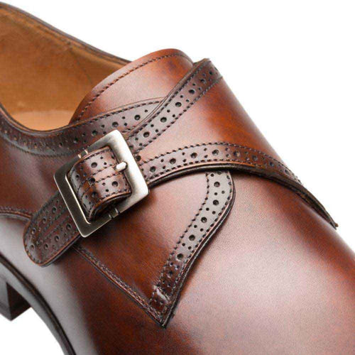 Cognac calfskin Mezlan monk strap shoe. Wingtip design with a broad strap and silver buckle. Features perforated detailing along the edges of the upper.

