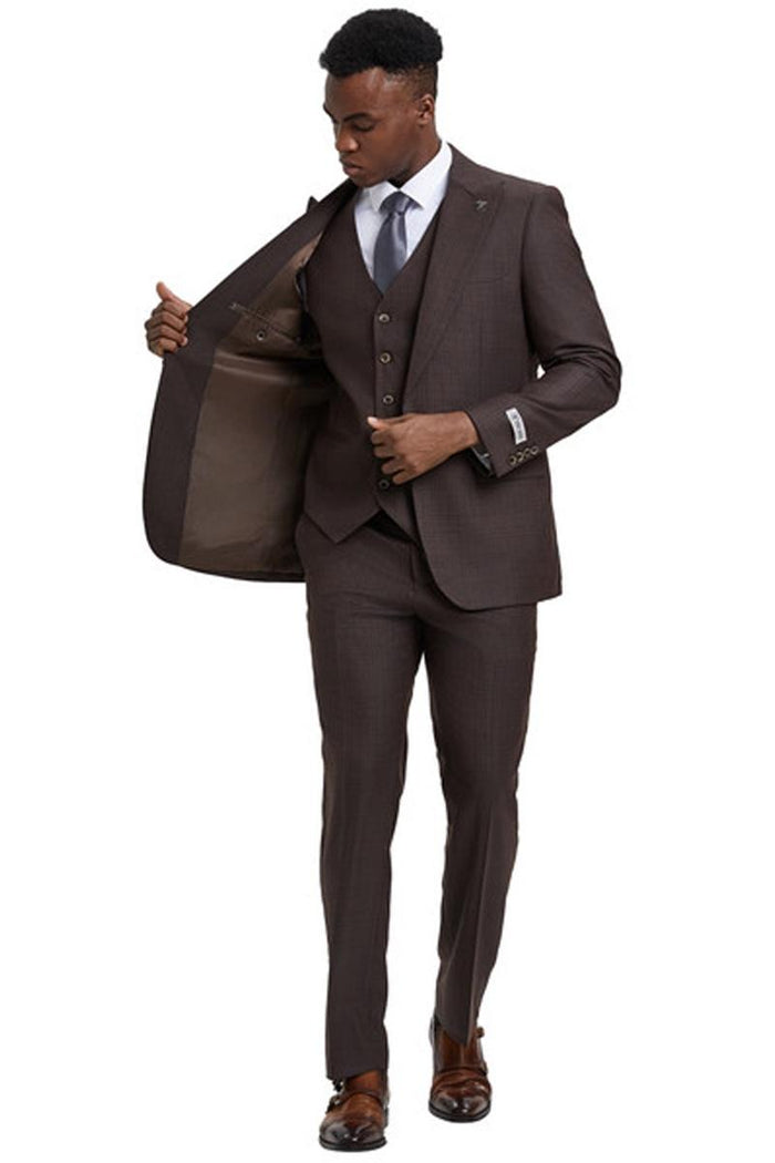 Brown windowpane plaid suit. One-button blazer with wide peak lapel, vested with three buttons. Smooth lining, slim-fit trousers. Tailored for a fitted look.
