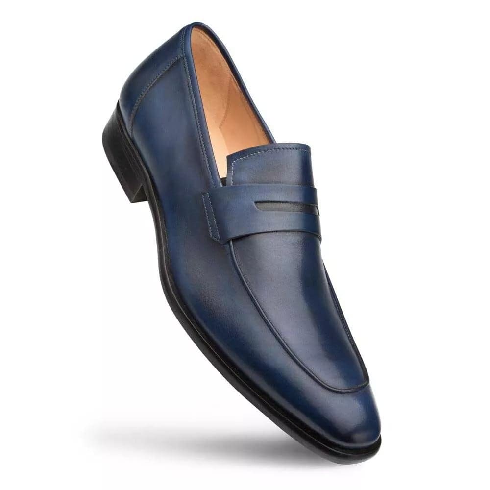 Navy burnished calfskin penny loafer by Mezlan. Sleek design with a rounded toe and low profile. Smooth, navy leather upper with classic penny strap detail. Features a slightly raised heel and flat sole.
