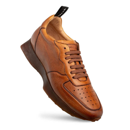 Gerardo men's cognac deerskin sneakers. Low-top with a textured cognac upper, rounded toe, and brown laces. Features toe perforations and a contrasting, darker sole with branding on the heel tab.

