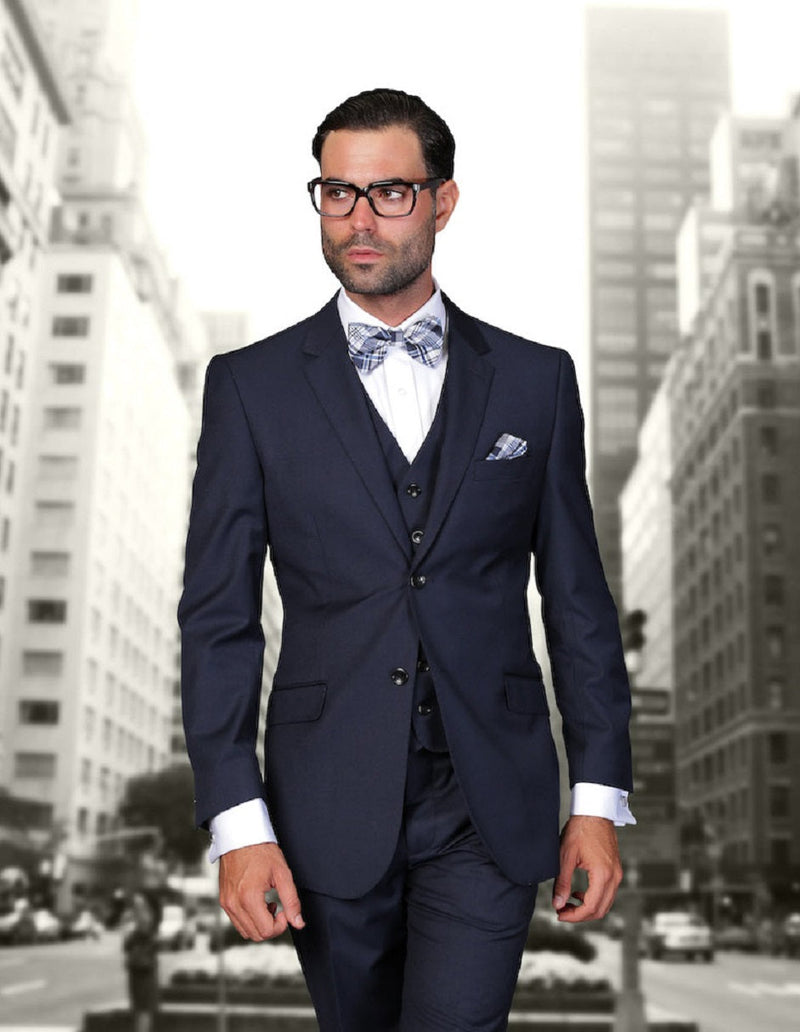 Navy modern fit wool suit for men: 2-button jacket, vest, and trousers. Smooth wool. Notched lapels, four pockets. White shirt with cuffed sleeves visible. Classic, streamlined design.