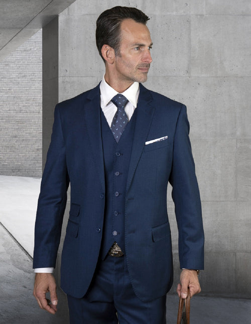Modern fit, sapphire blue men's suit. Features a 2-button blazer, vest, & straight-leg trousers. Solid weave with pick stitch detail. Includes a breast pocket with a white pocket square. Worn with a white shirt and patterned tie.