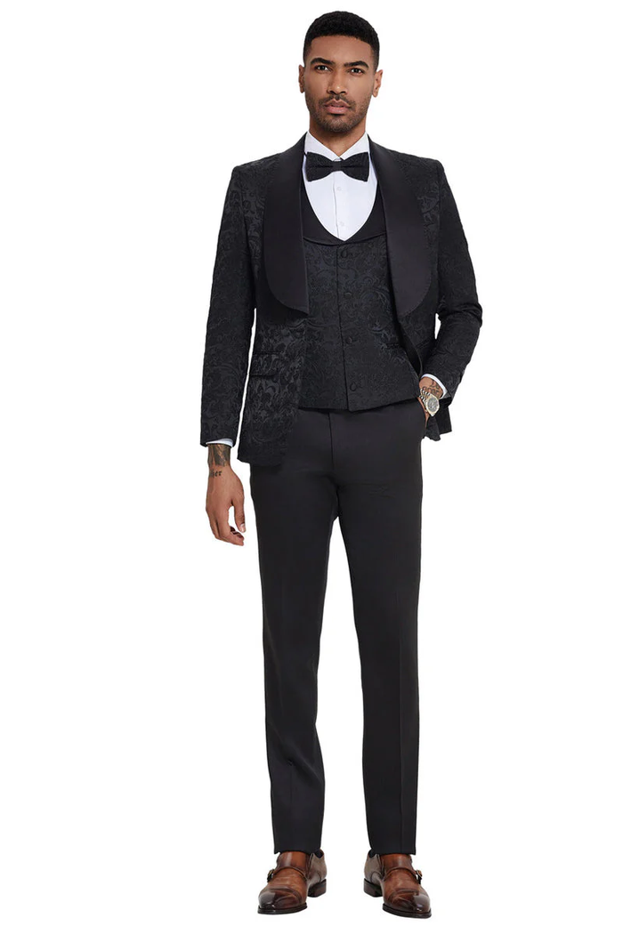 Black men's designer tuxedo with paisley jacket and shawl lapel. Includes a fitted vest and straight-leg trousers, creating a formal and cohesive look. Perfect for weddings and proms.
