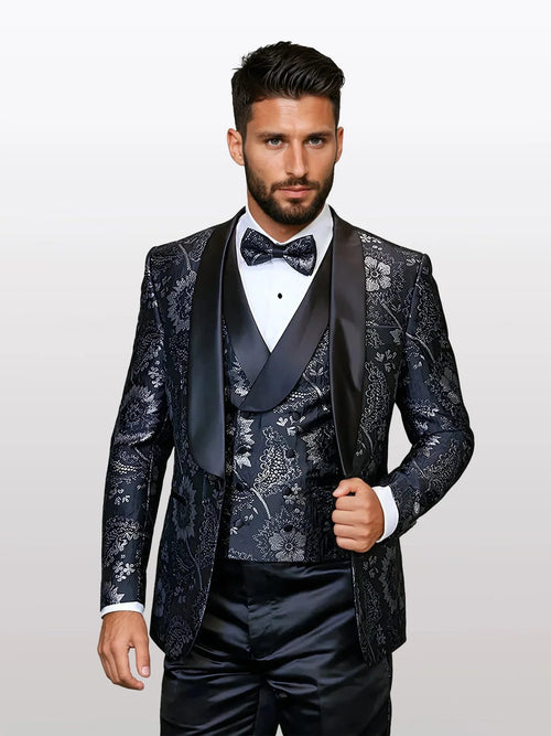 Men's black floral patterned vested tuxedo features a fitted structure with a satin lapel and a floral design in varying shades of black and grey. The ensemble includes a matching bowtie.