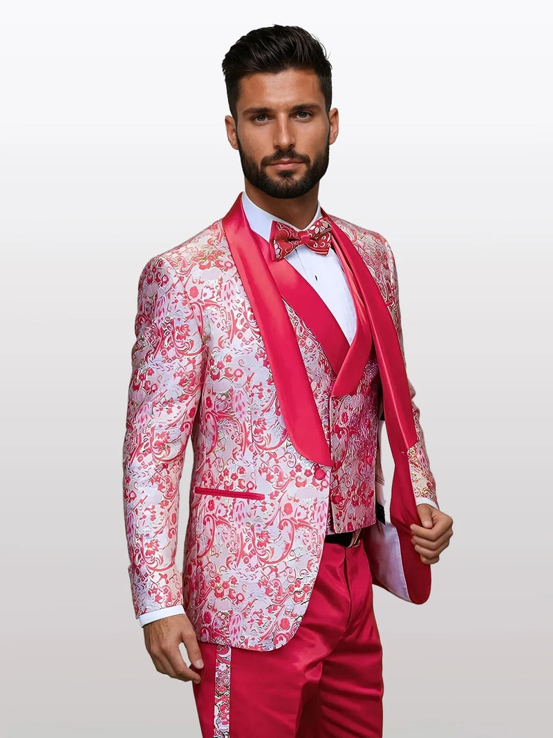 A men's coral-patterned vested tuxedo features a pink floral design on the jacket, complemented by a solid pink bowtie and matching pink trousers, all with a shiny finish.