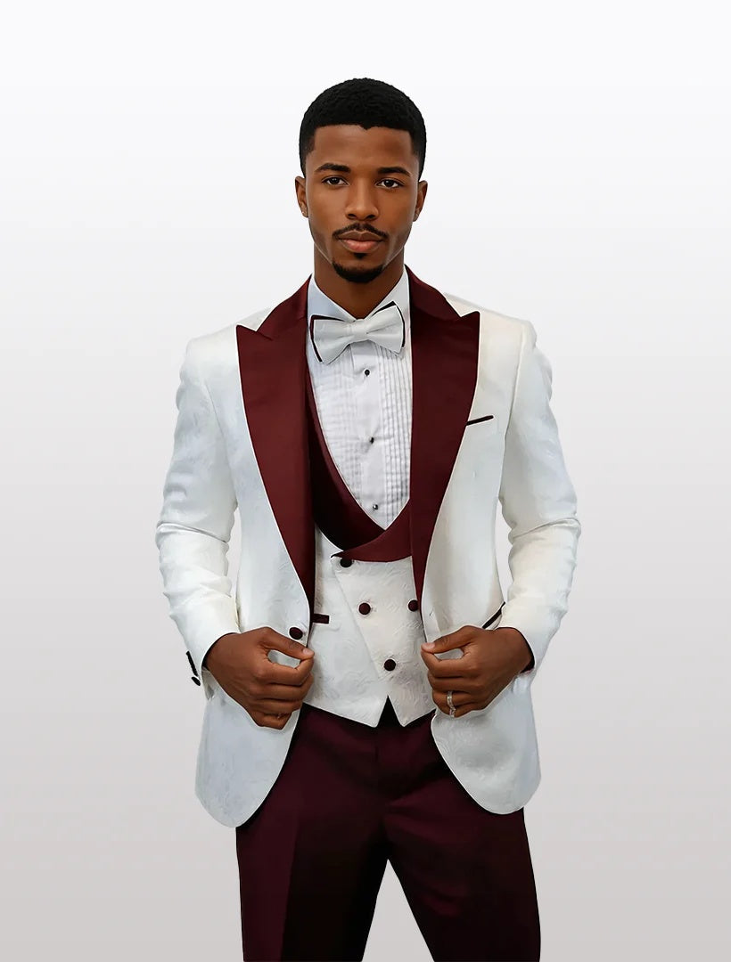Men's white tuxedo with burgundy peak lapels features a double-breasted vest and bow tie. The suit is tailored with visible buttons and a textured fabric on the vest.