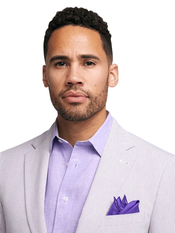 Men's lavender seersucker blazer in cotton with striped pattern. Fitted design, sleek collar, and a deeper purple pocket square.
