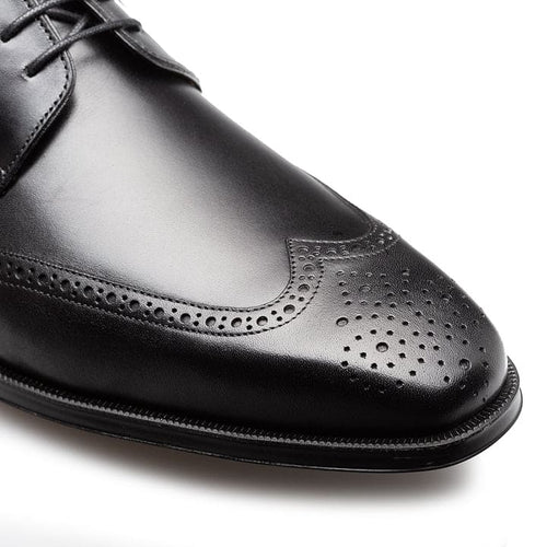 Men's black wingtip derby shoes. Sleek leather upper, pointed toe, decorative perforations. Narrow sole with slight front curvature. Smooth finish.
